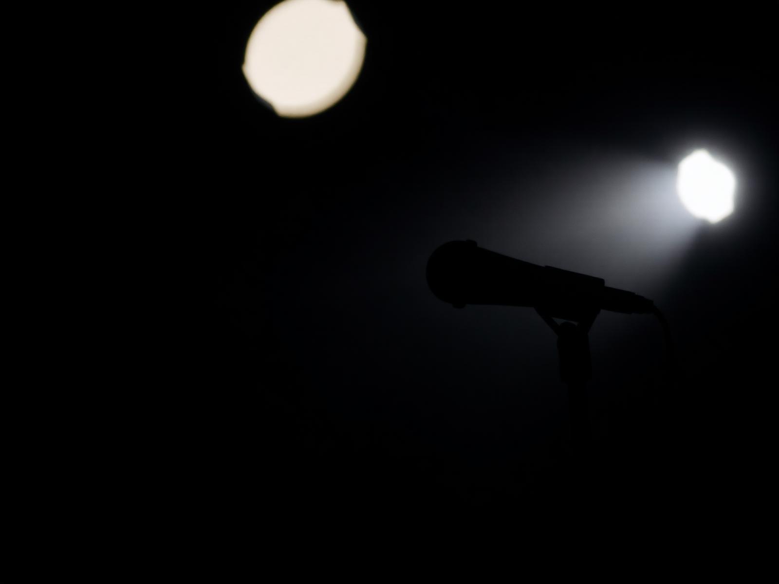 A microphone silhouette in a dark room lit by a single rim light